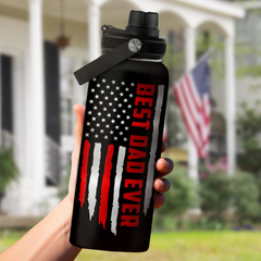 Black water bottle with American flag design and 'Best Dad Ever' text, held in front of a house with an American flag.