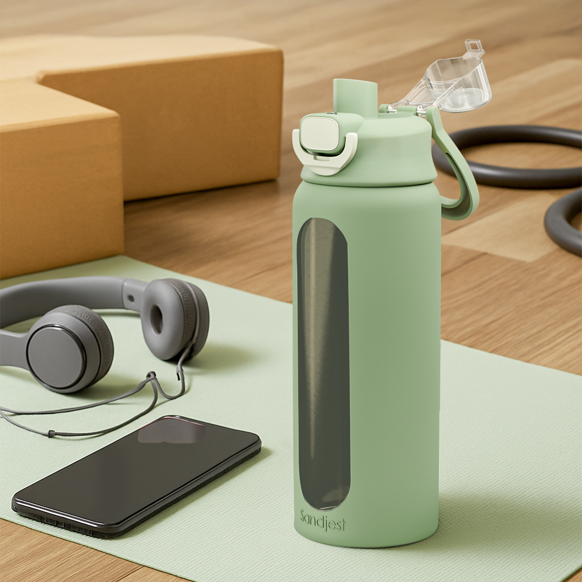 Green water bottle with a phone and headphones on a green mat