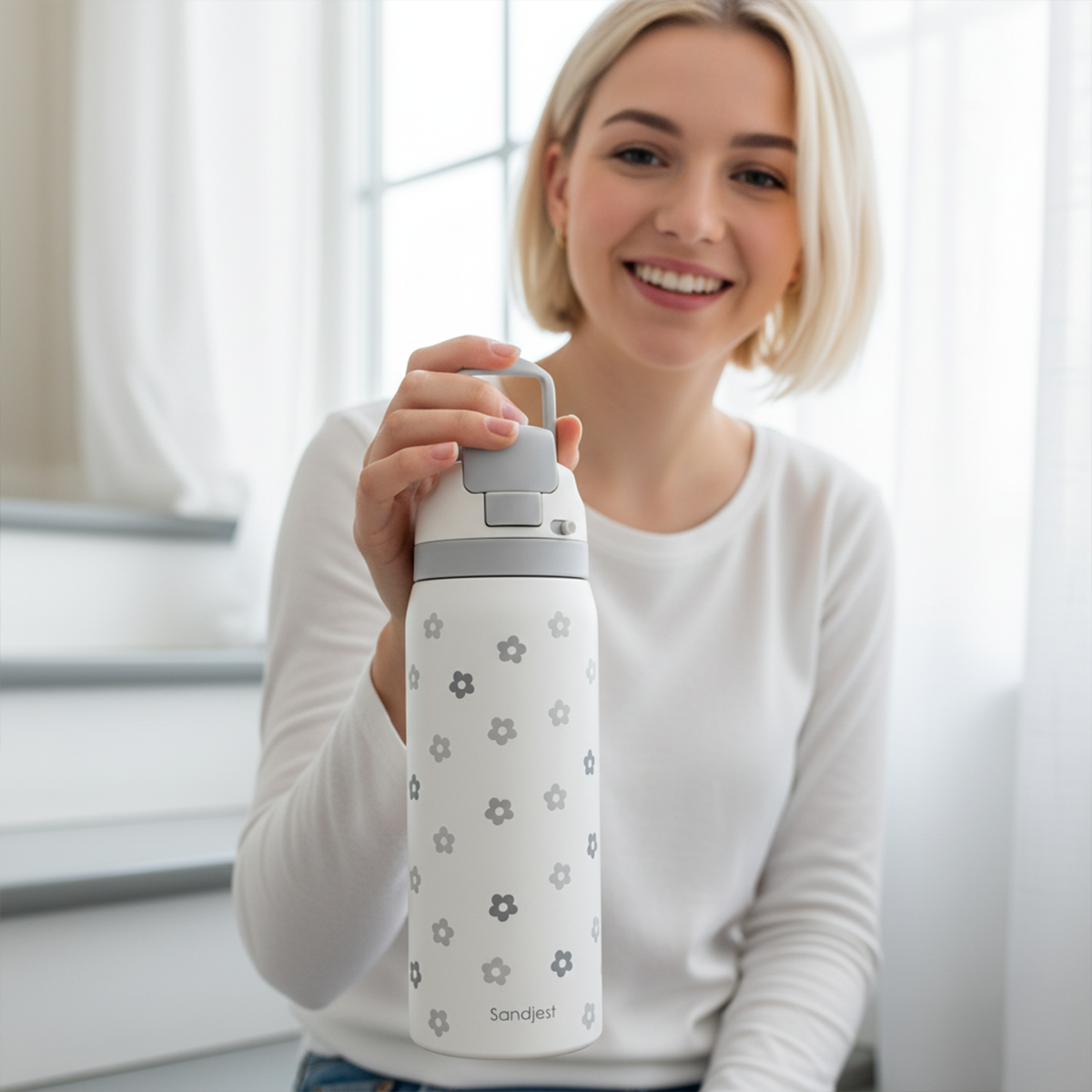 Woman holding a white water bottle with gray floral patterns indoors