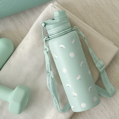 Light green water bottle with floral design on a beige surface