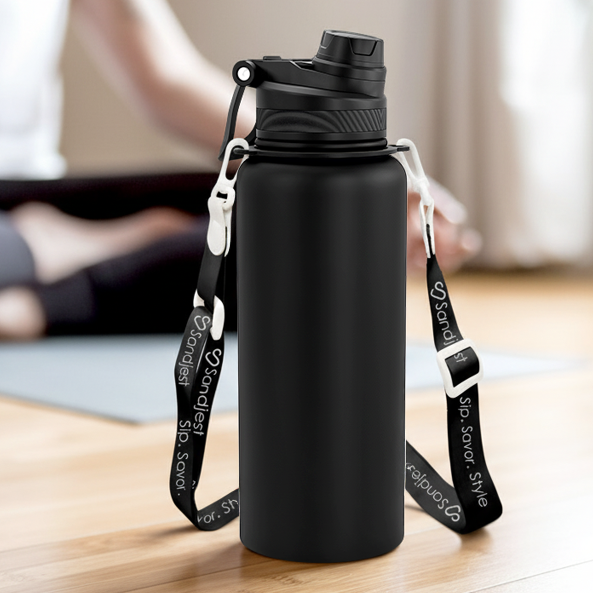 Black water bottle with a strap on a wooden floor
