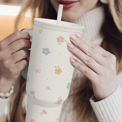Person holding a floral-patterned mug with a straw