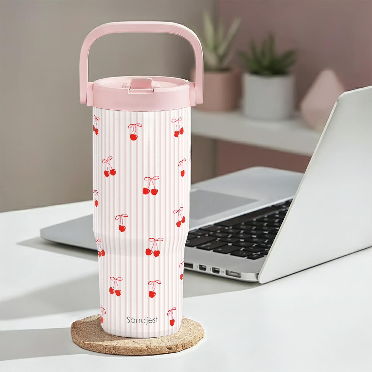 White thermos with red cherry pattern on a desk with a laptop