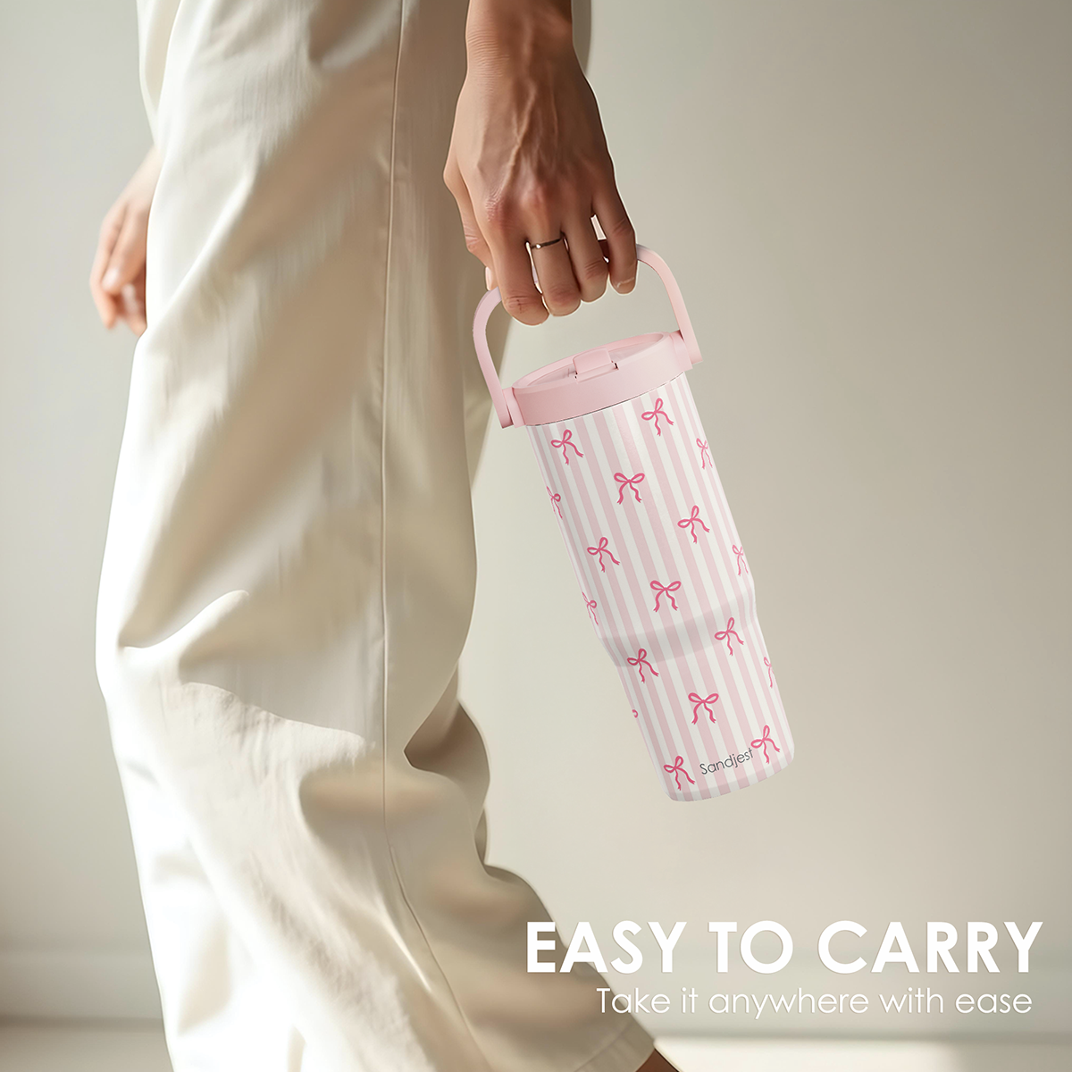 Person holding a pink water bottle with bow pattern and text 'EASY TO CARRY' on a neutral background