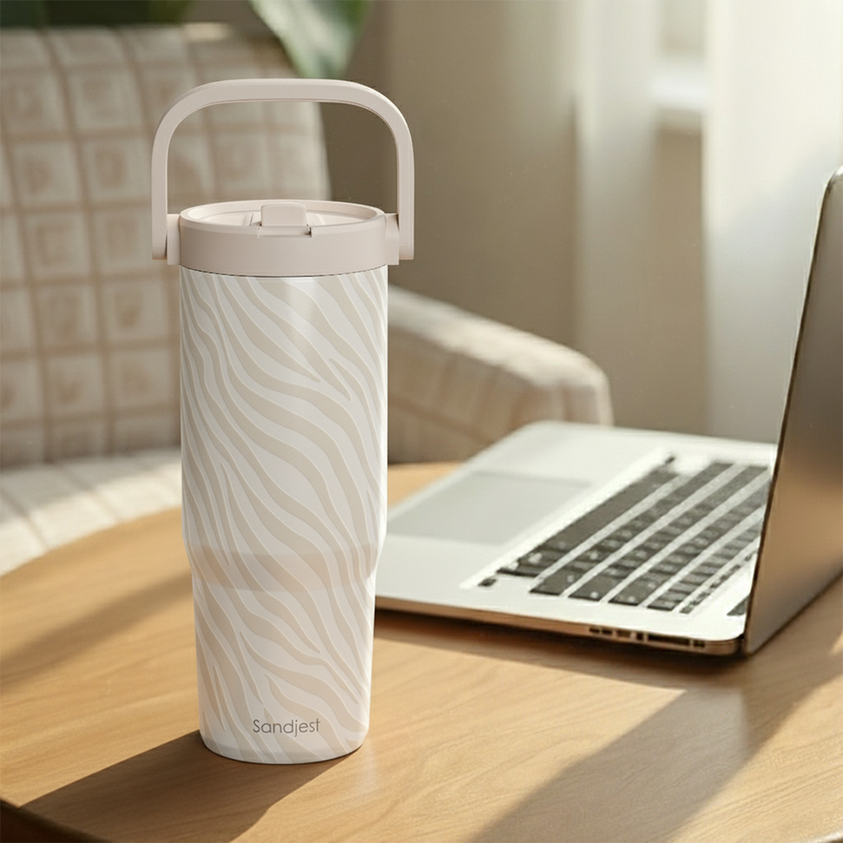 White tumbler with gray pattern on a wooden desk next to a laptop