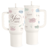 Two white insulated stainless steel tumblers with handles and straws, featuring pastel-colored text and designs such as hearts and leaves, with one side showcasing phrases like 'You are', ' Accepted', and 'Forgiven'.