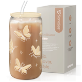 A beige glass bottle with butterflies pattern, accompanied by a bamboo lid and a glass straw, displayed next to its packaging box.